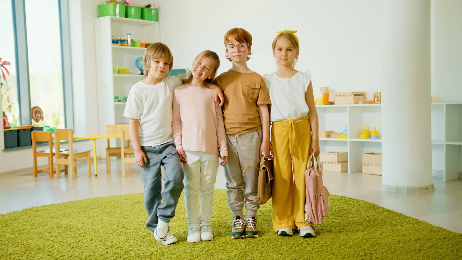 Four school-age friends standing together in a bright activity room